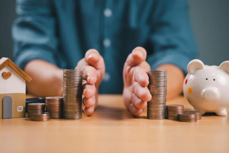 Divorce law and inheritance separation concept. Hand separate saving money, finance, home loan, debt return with piggybank and wood house. Bank business investment. Man separate stack coin on table