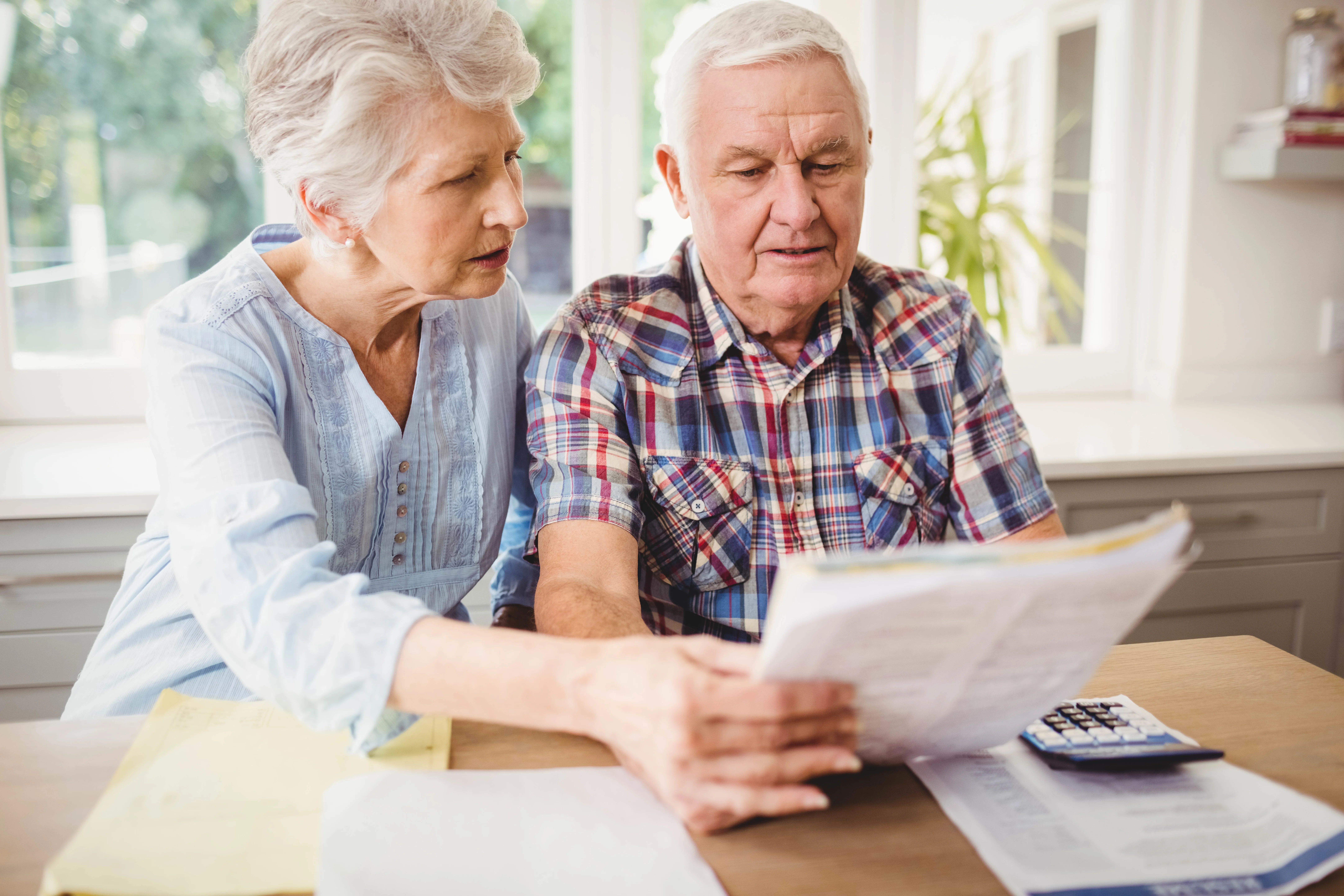 Worried senior couple checking their bills at home